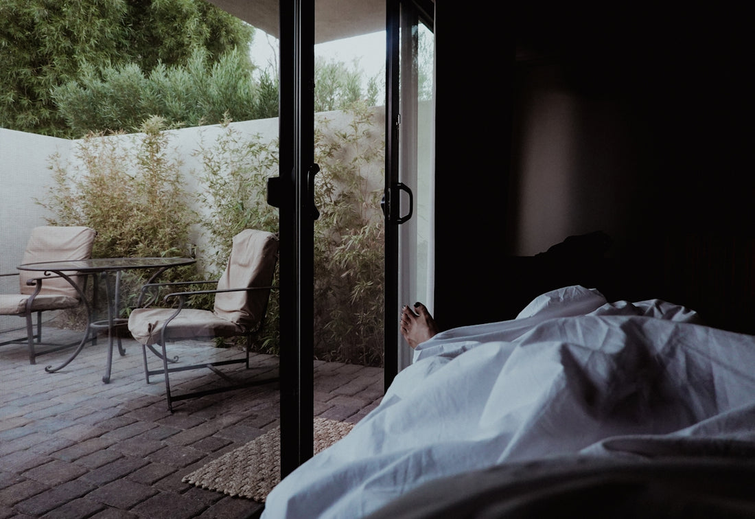 a person laying in a bed next to a sliding glass door