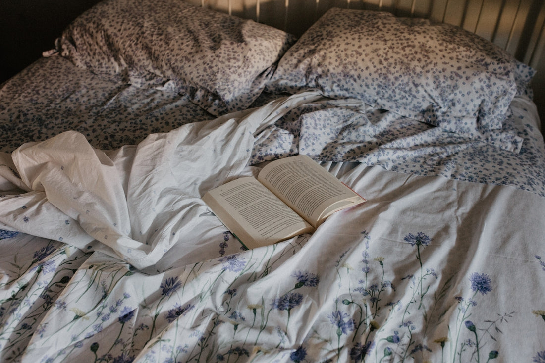 an open book is laying on a messy bed