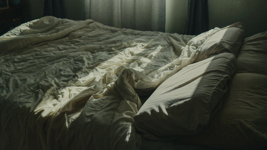 an unmade bed with a window in the background