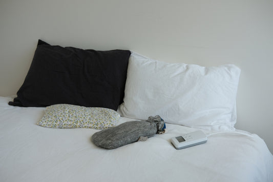 A white bed with a black pillow and a remote control