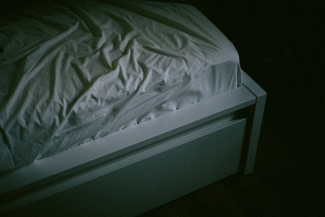 A bed with a white comforter in a dark room