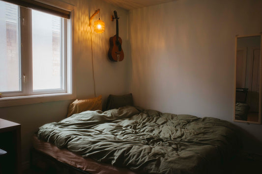 A cozy bedroom with a guitar and bed.